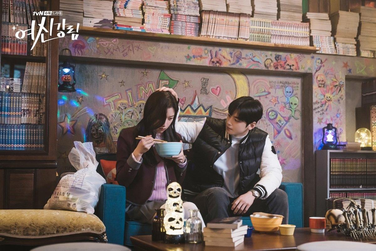 ฉากจากซีรีส์ 'True Beauty' ในร้านกาแฟที่มีหนังสือและผนังตกแต่งด้วยลวดลายศิลปะ