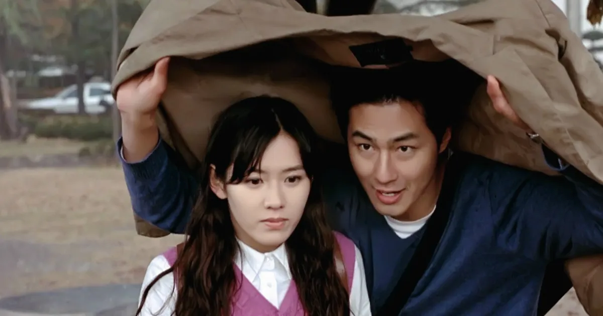 韩国经典电影海报，展示了两人用外套遮雨的场景，传递出浪漫和怀旧的气息。