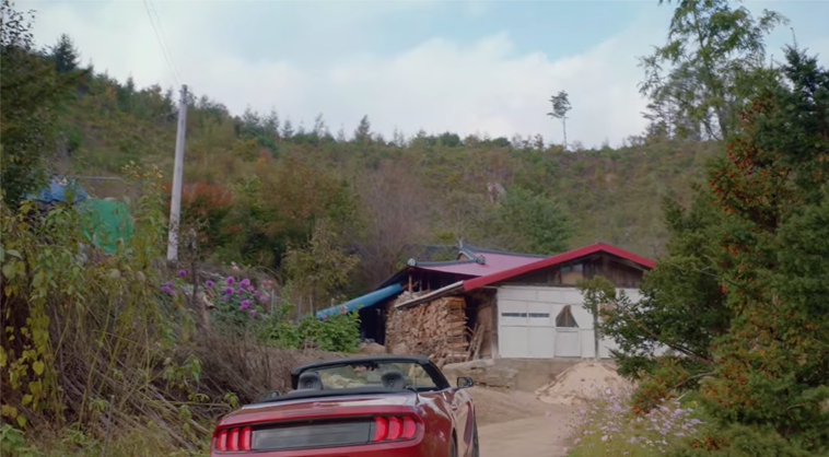 一輛紅色敞篷車停在上古舍里路的鄉村小屋前，背景顯示山林景色，該地點出現在韓劇《Run On奔向愛情》中。