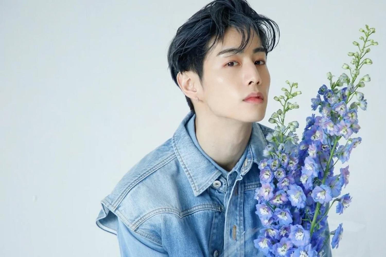 GOT7 멤버 중 한 명이 데님 셔츠를 입고 꽃을 들고 있는 모습