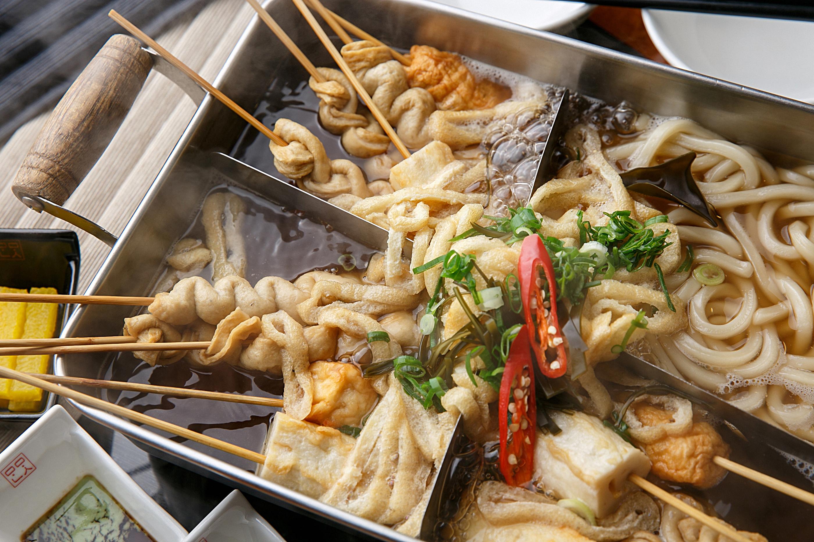 韓国式おでんが並んだ屋台の様子。串に刺さった魚介の練り物が大鍋で煮込まれ、湯気が立ち上る様子。