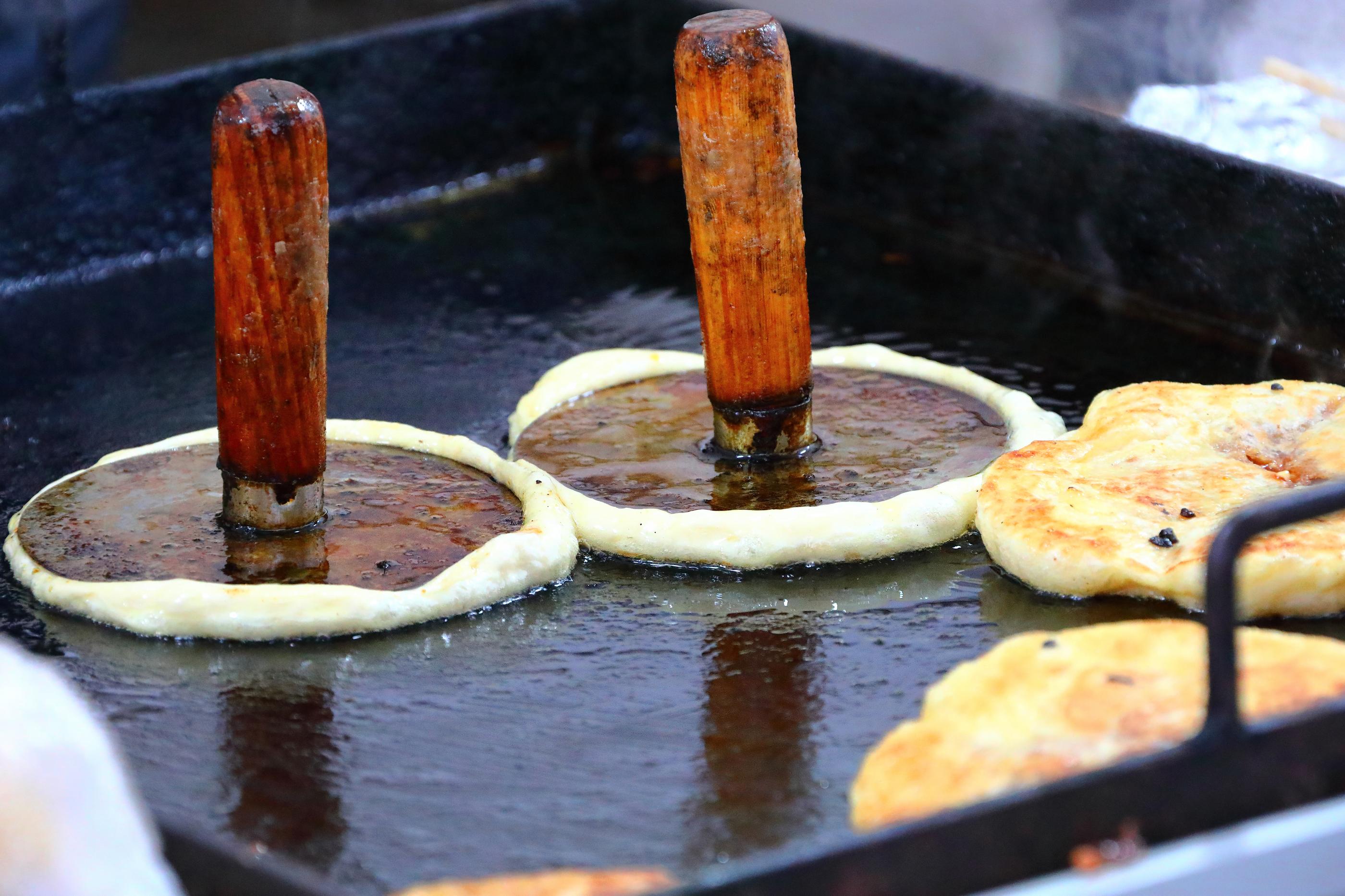 ホットックが鉄板で焼かれている様子。溶かした砂糖のフィリングが生地からはみ出す韓国の人気デザート。