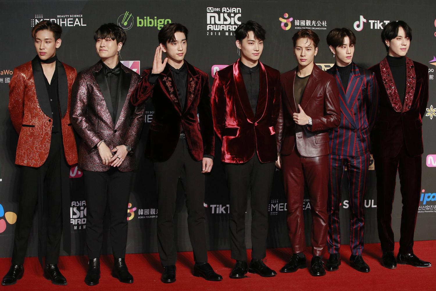 สมาชิกวง GOT7 บนเวทีรับรางวัลในงานประกาศรางวัลแห่งหนึ่ง ทุกคนสวมชุดสูทสีแดงและดำ