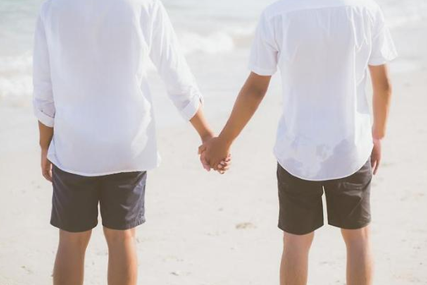 兩人手牽手在沙灘上走，象徵同性戀情。