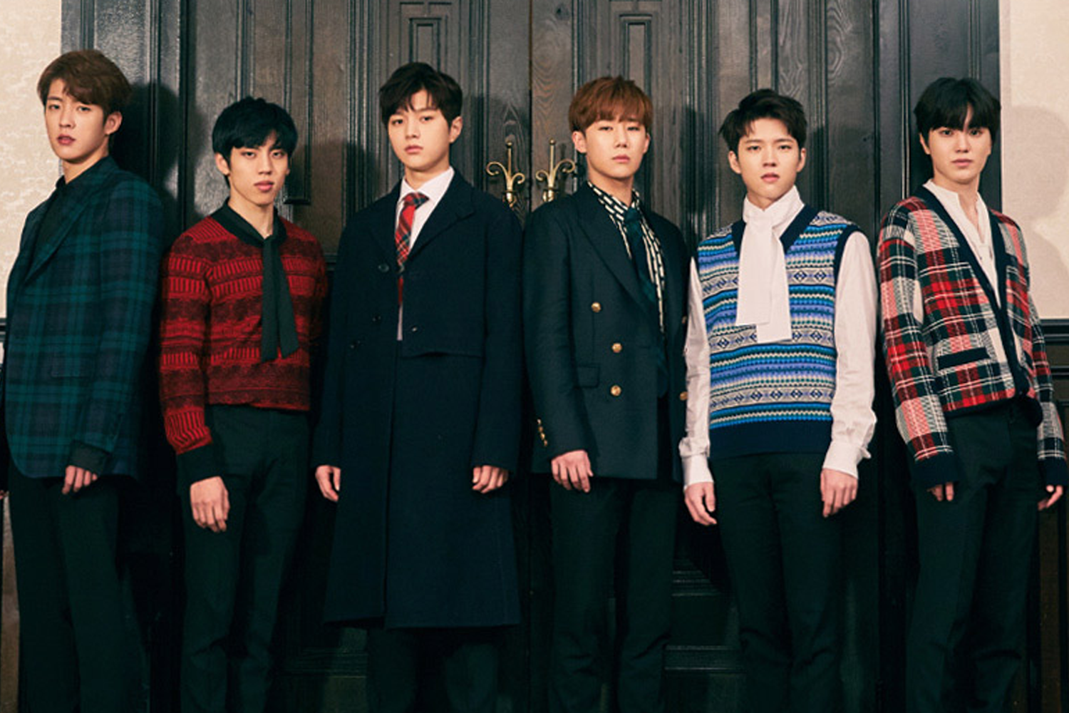 一羣男子偶像團體成員站成兩排，背景是一扇木門，他們身穿各式格子花紋和時尚服裝，迎合拍攝氛圍。