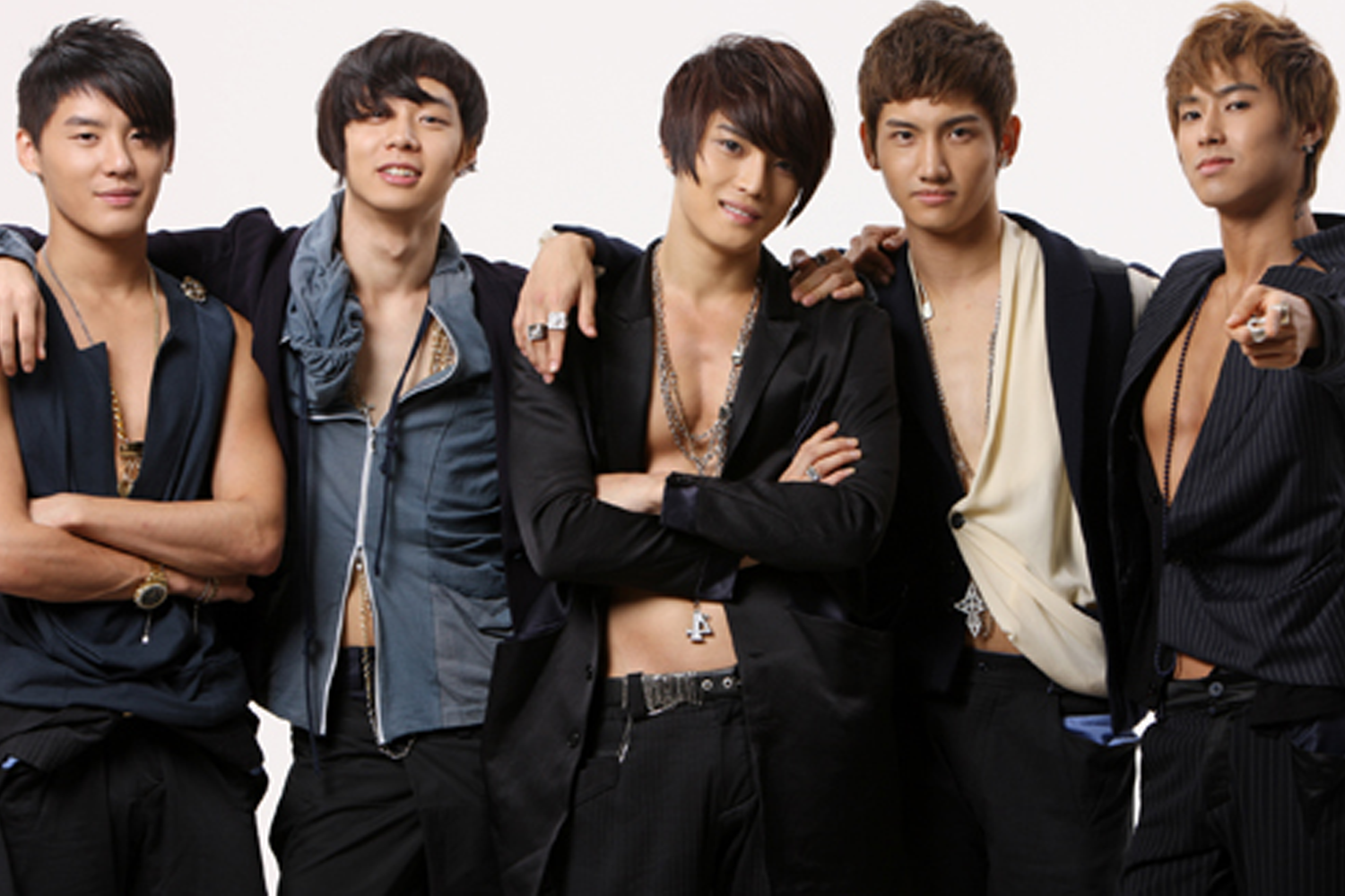 五位身材高挑的男團成員站在一起，穿着大膽而時尚的黑色套裝，他們展示出自信和現代感，背景為白色。