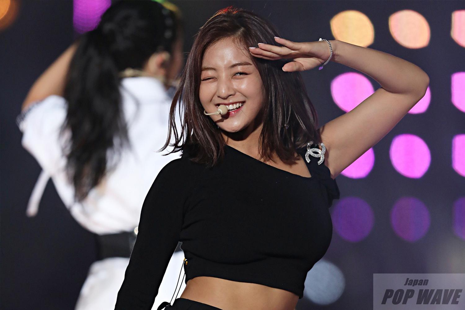 韓國女偶像在舞台上展示自信的表演姿態，穿著經典黑色服裝。