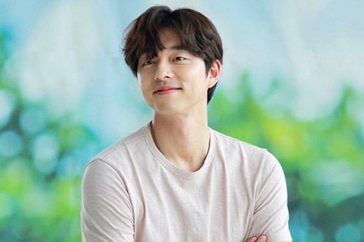 韓國演員孔劉穿著白色T恤,坐在沙發上,背景為淺色牆壁,陽光投射在臉上。