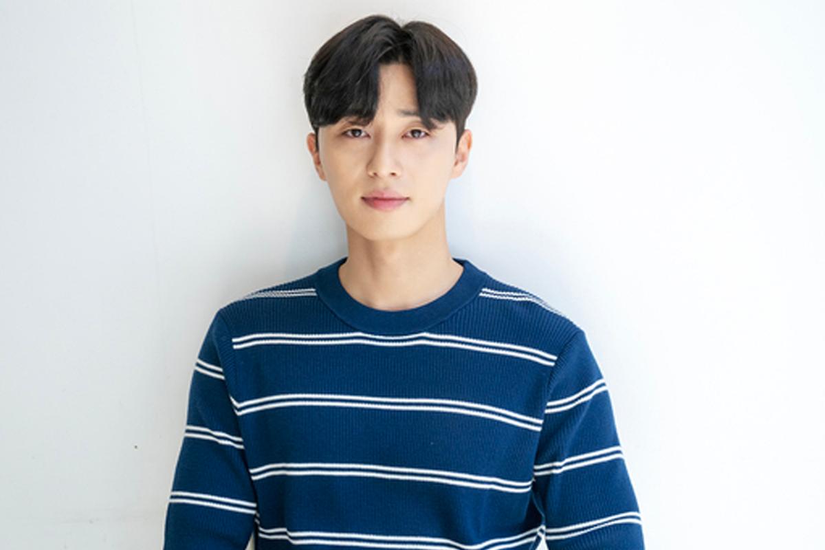 韓國演員樸敍俊穿著大衣，微微側身面向鏡頭，背景為柔和的灰色。