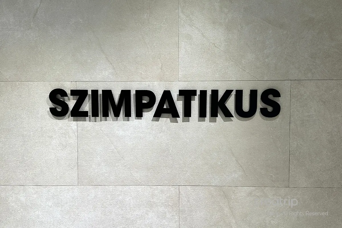 Szimpatikus 레스토랑 로고가 벽에 장식되어 있는 모습. 세련되고 고급스러운 분위기를 암시하는 디자인입니다.