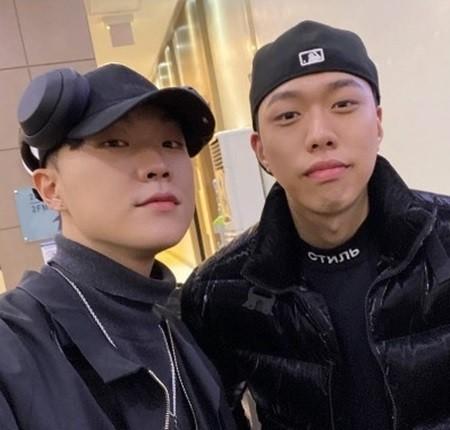 チェック柄のジャケットを着たKhundi Panda。彼の動作はスタイリッシュで、壁際でポーズを取っています。