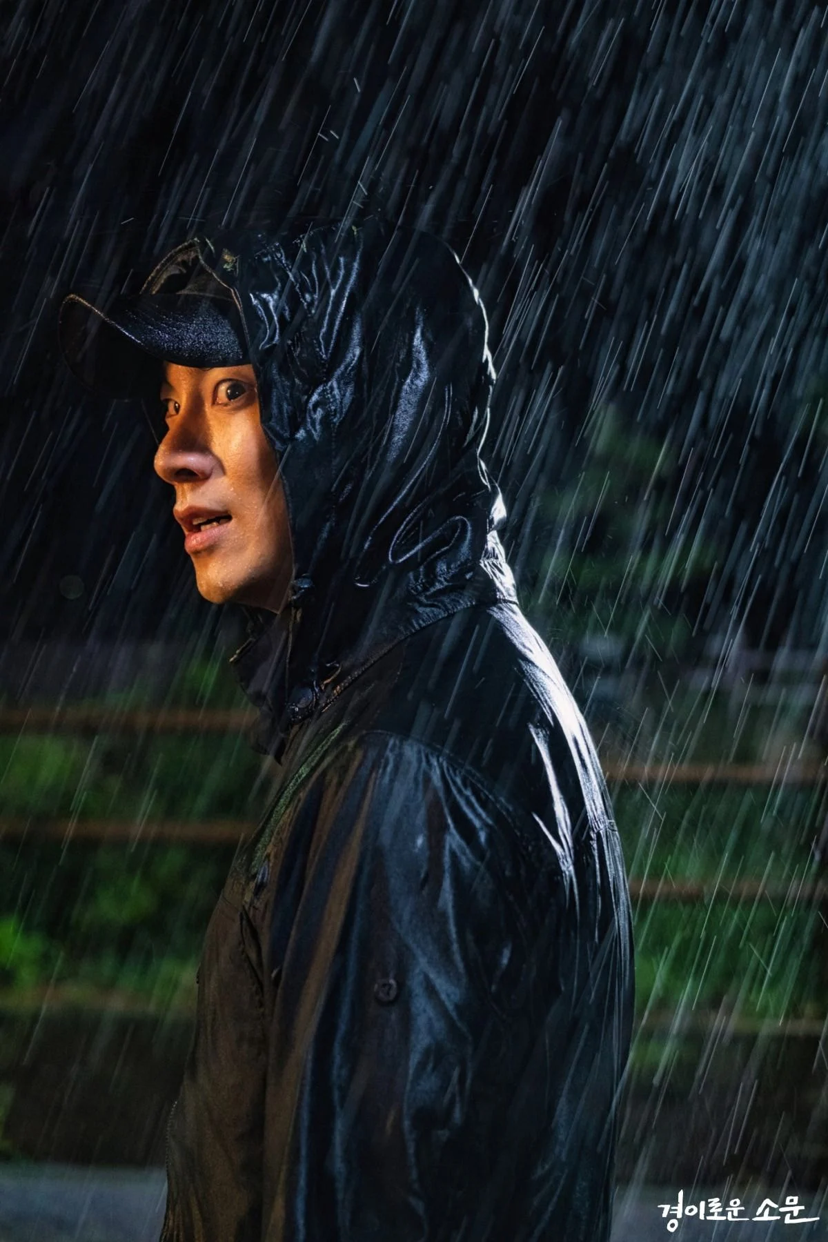 在雨中穿著黑色雨衣的男子,側立在鏡頭前。