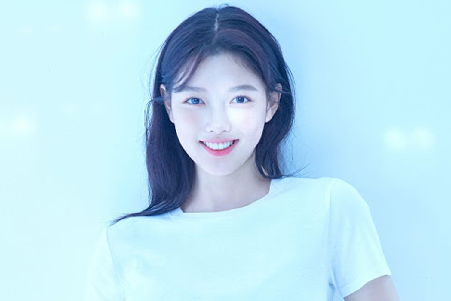 金裕貞身穿白色上衣，背後是柔和的米黃色背景，營造出温馨淡雅的感覺。