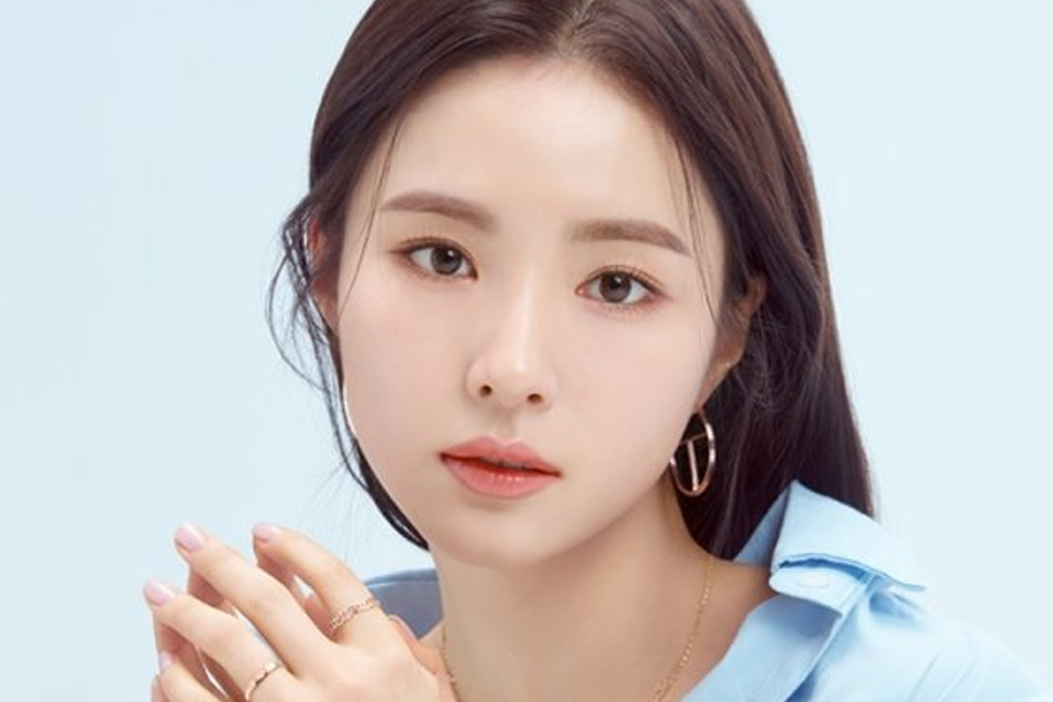 申世景身著藍色襯衫，背景白色，突顯她的青春活力和時尚感。