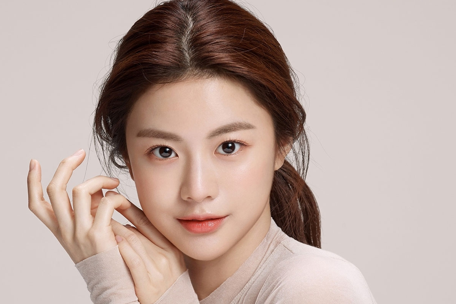 高允貞穿著淡粉色上衣，梳著長髮，配上柔和背景，盡顯她的温柔氣質。