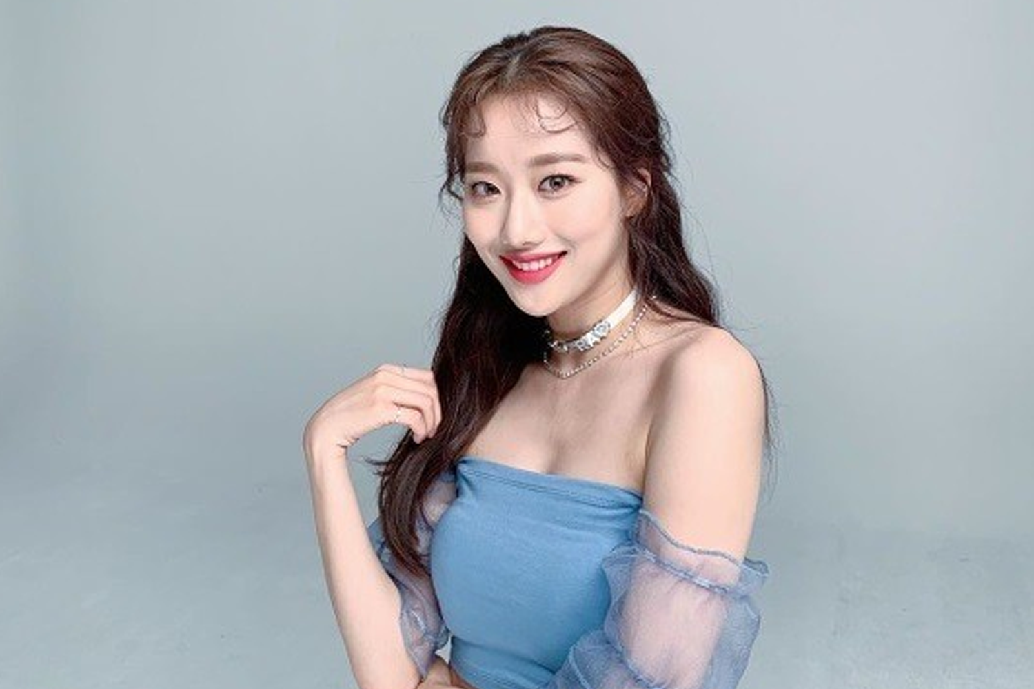 李娜恩身著藍色無袖連身裙，背景灰色，展示出她成熟端莊的一面。