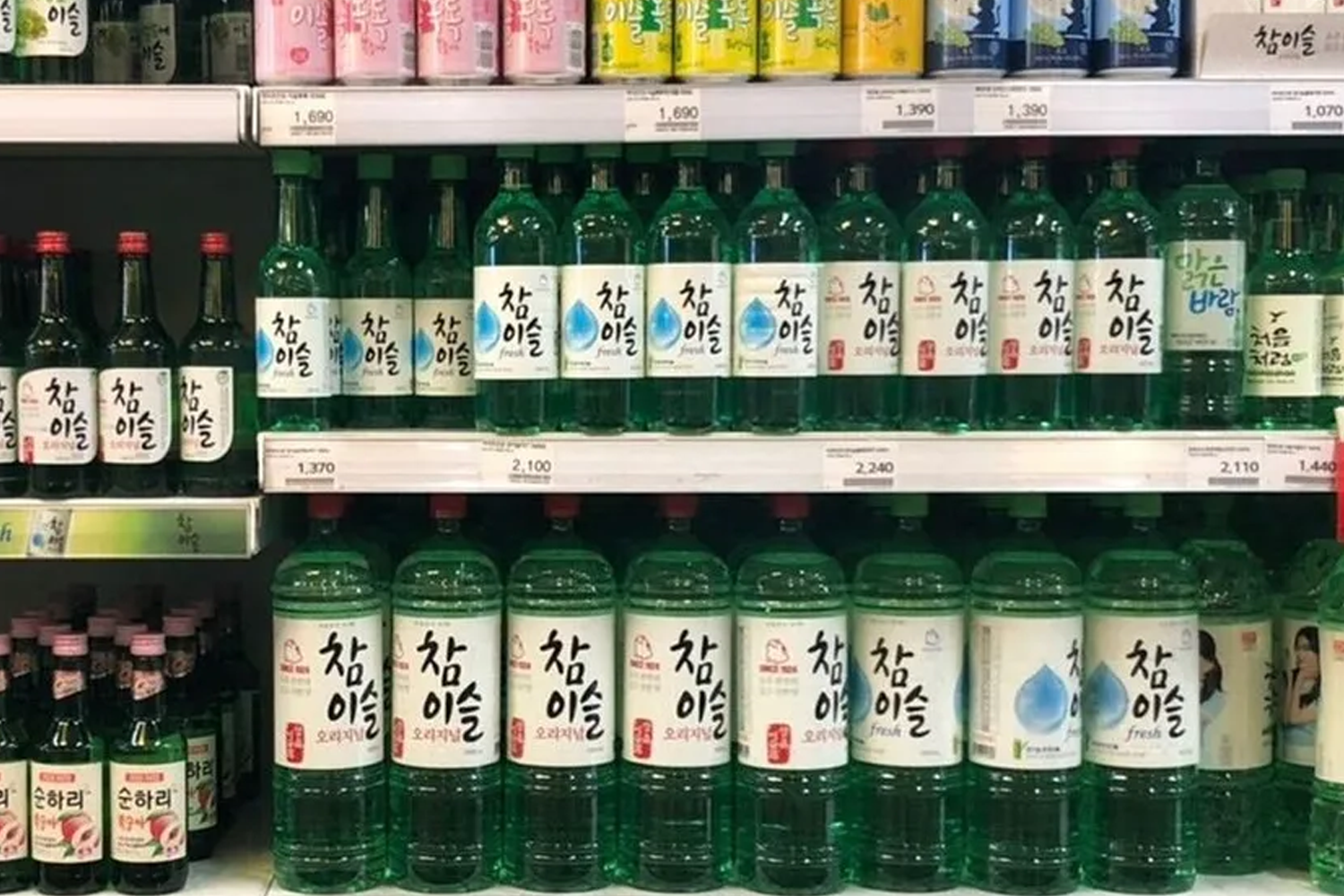 超市货架上的韩国烧酒瓶，绿色透明瓶和白色标签，按品种排列。