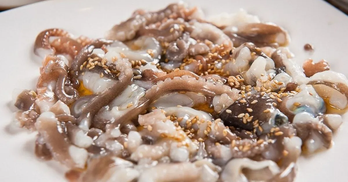 韩国传统菜肴，生章鱼，撒上芝麻和调料，展示独特的韩国风味食品。