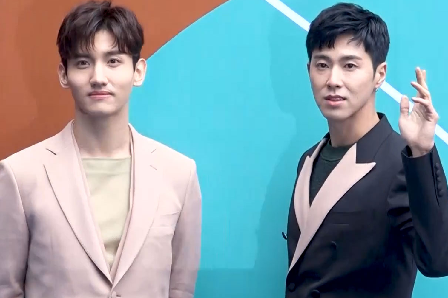 东方神起成员在户外的合照，两人都穿着正装。