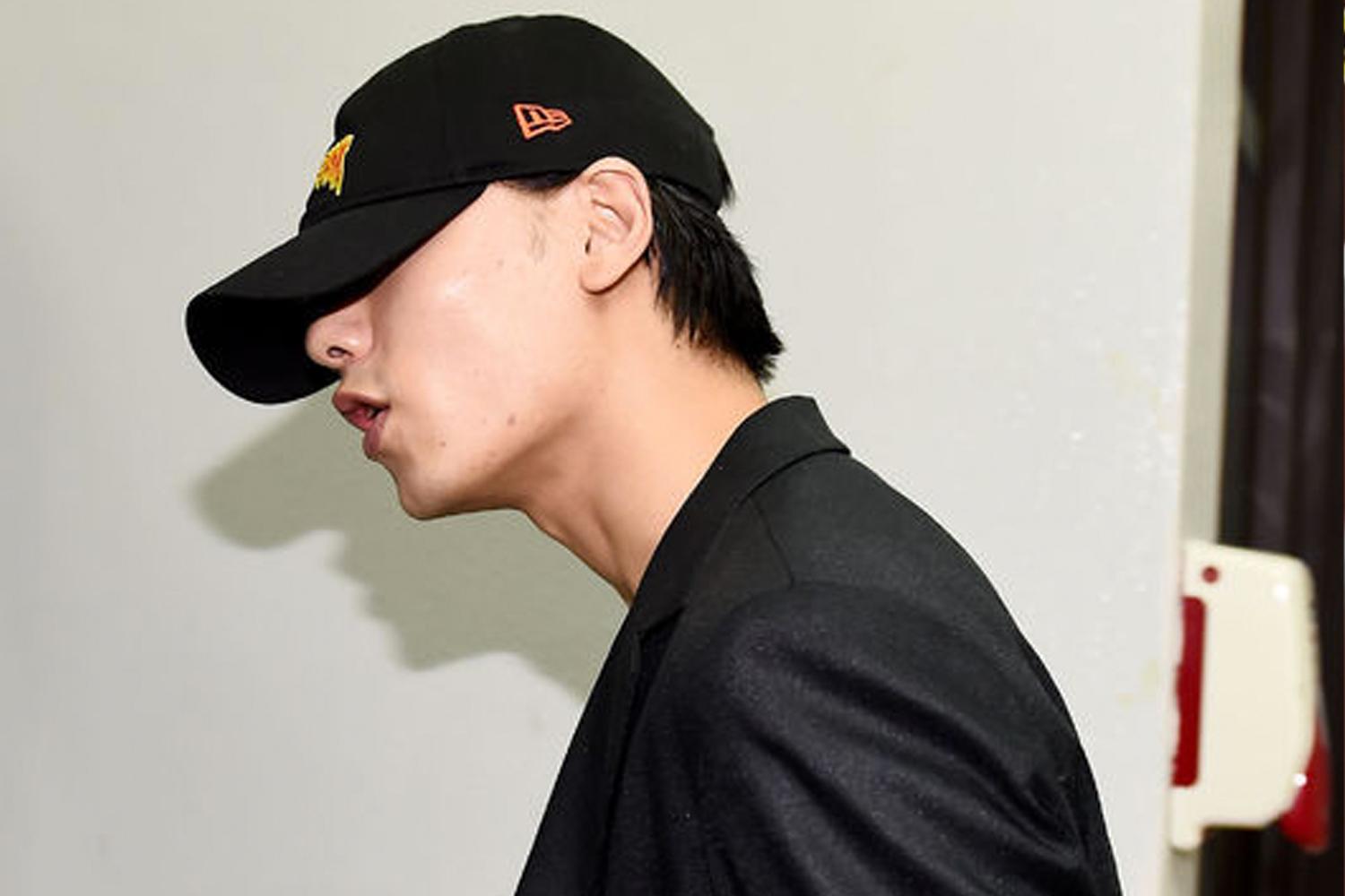 ชายคนหนึ่งสวมชุดสูทและหมวกแก็ปสีดำ ขณะเดินทางไปที่สำนักงานตำรวจ