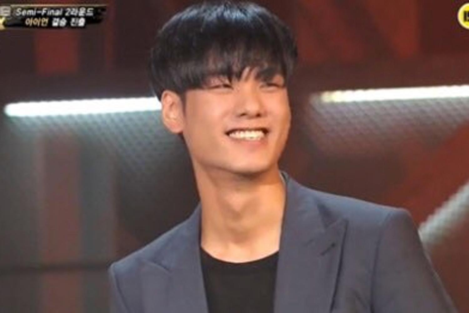 แรปเปอร์คนหนึ่งในชุดสูทสีดำระหว่างการแข่งขันในรายการ Show Me The Money 3