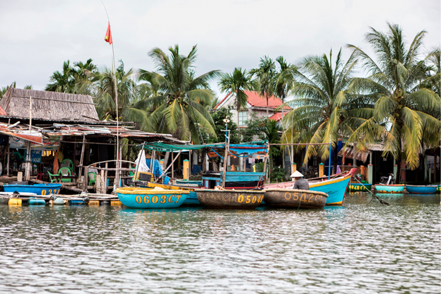 越南峴港的水上船隻，背景為椰樹和小屋，隨和的氛圍吸引韓國家庭的度假勝地選擇。