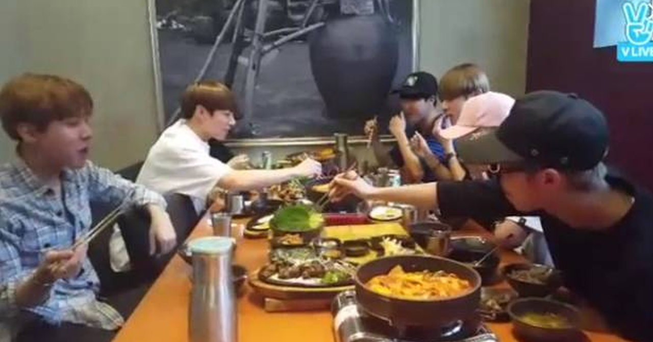 一羣人在韓國餐廳中圍坐在一張桌子旁分享餐食，這代表著韓國獨特的飲食文化。