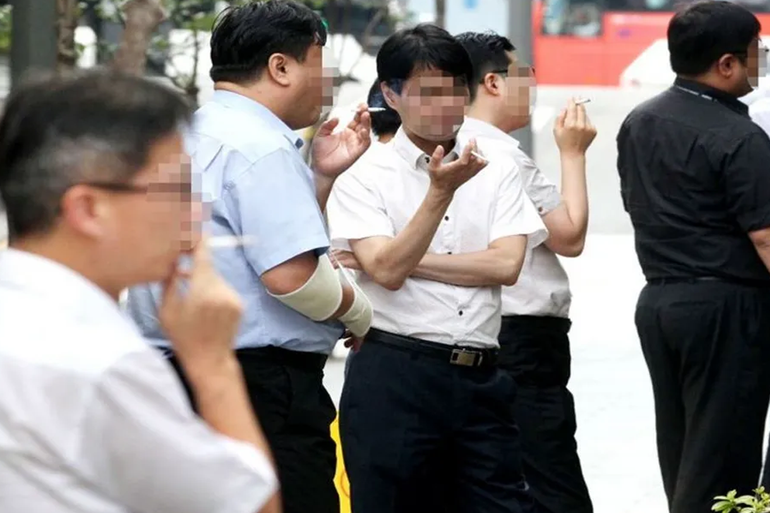 一群人在户外吸烟，韩国政府计划提高烟价以改善公共健康。