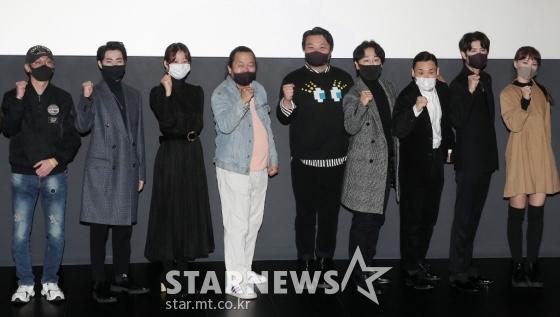 映画『この中に宇宙人がいる』の試写会に参加した出演者たちが並んでポーズを取る。写真は、ソウルのロッテシネマ建大入口でのイベントで撮影されたもので、俳優たちが団結を示すために拳を挙げているシーンが映されている。