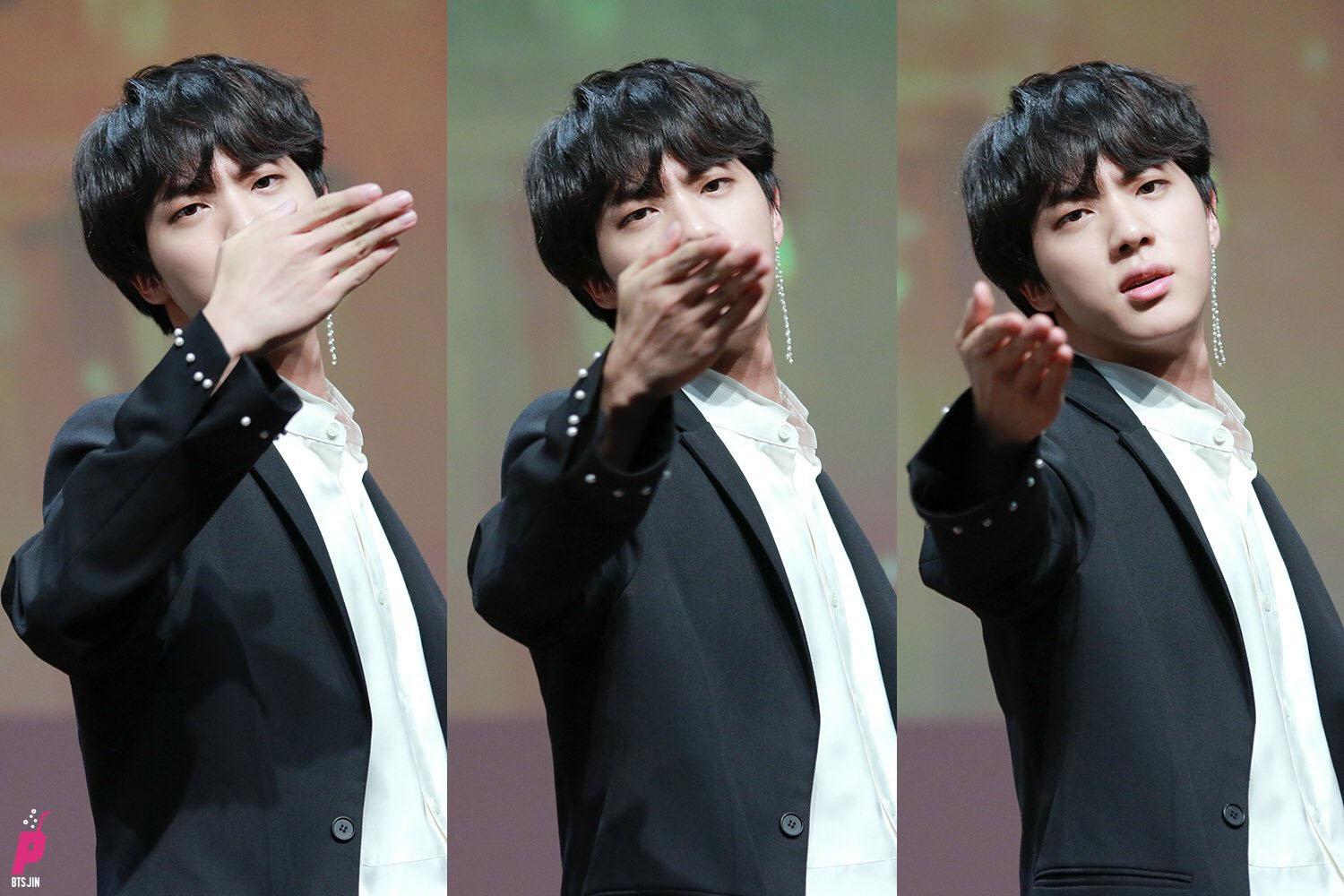 韓國男偶像在舞台上輕鬆自然地做出飛吻動作，展現其熟練的舞台表現力。