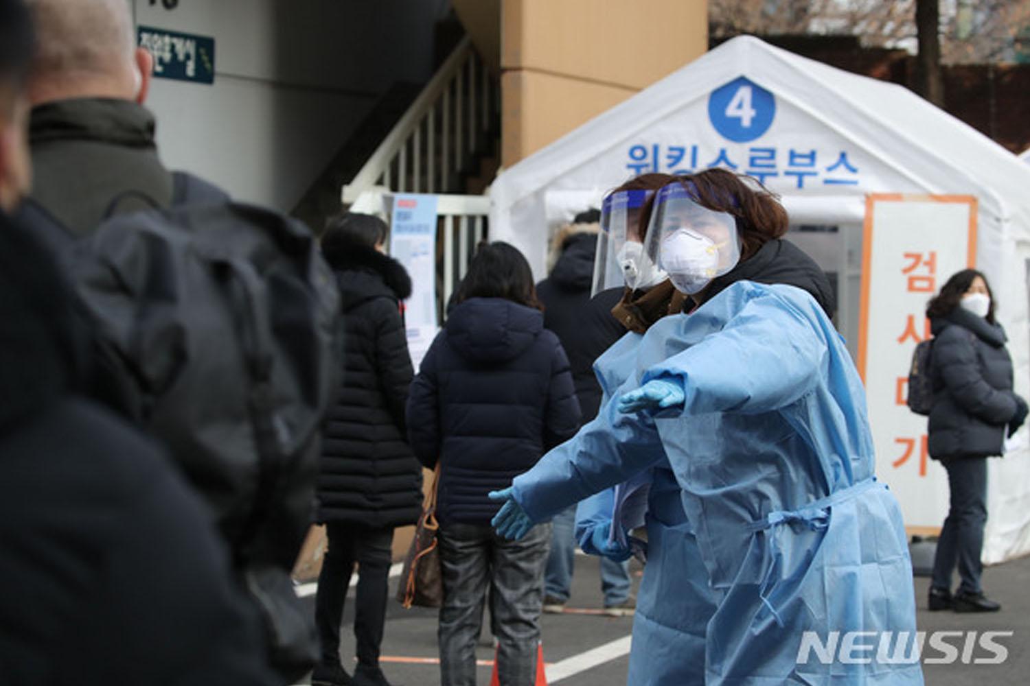 เจ้าหน้าที่สาธารสุขในชุดป้องกัน COVID-19 ให้คำแนะนำผู้ที่มาตรวจโควิดที่สถานีทดสอบในกรุงโซล เกาหลีใต้
