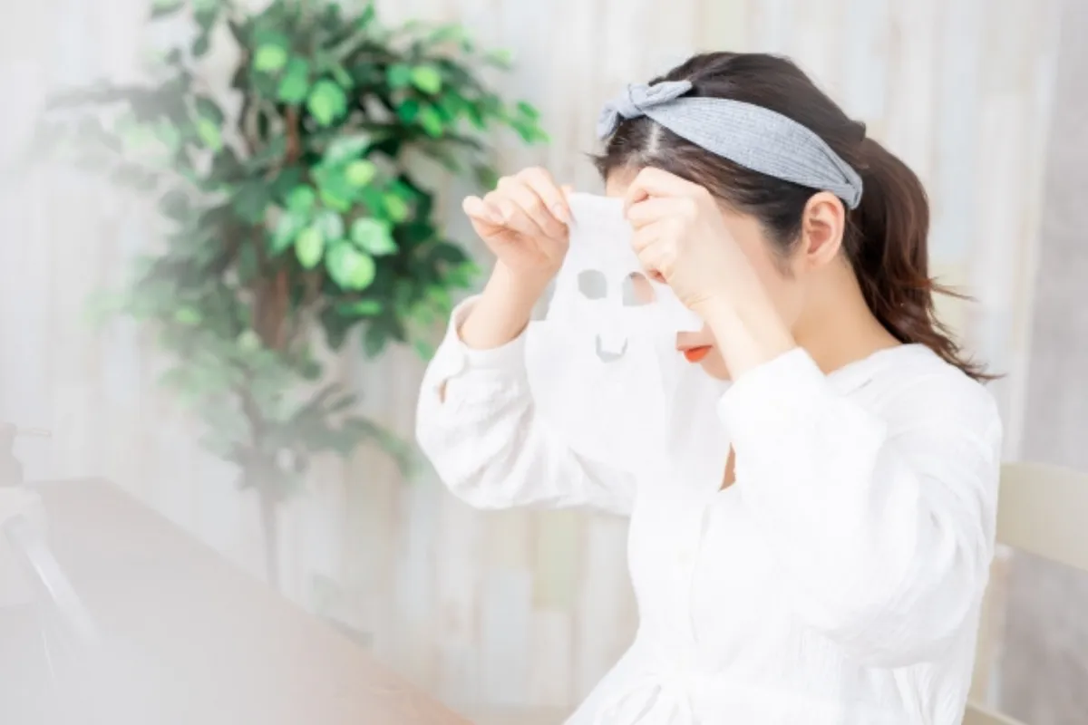 ภาพหญิงสาวเตรียมมาสก์หน้าขณะนั่งอยู่ในห้องที่มีต้นไม้ประดับอยู่ข้างๆ