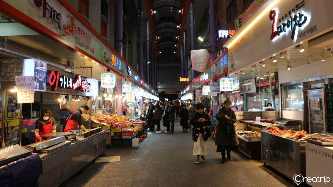 Street food enthusiasts exploring Bupyeong Market at night, captivated by the diverse options of snacks and meals available.