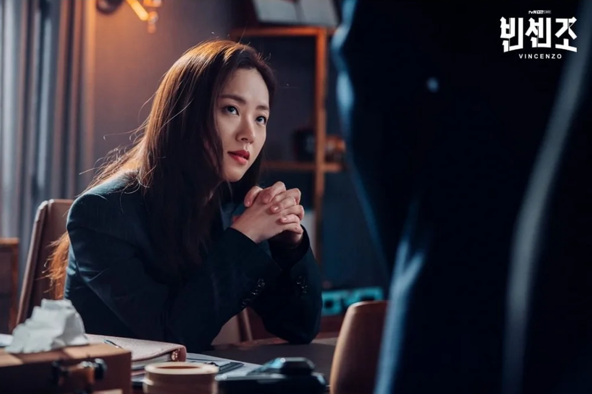 Jeon Yeo-been with both elbows on desk and hands together, talking to someone on K-drama Vincenzo