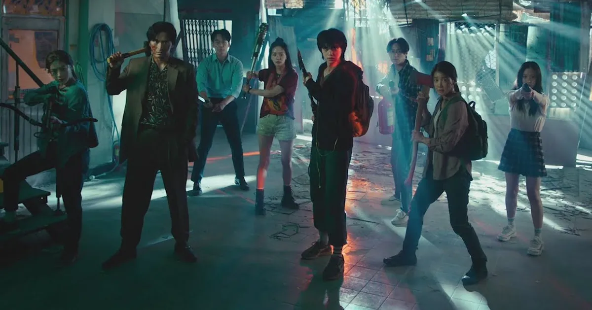 韓國電視劇《Sweet Home》中幾位角色在建築物內持武器進行防禦姿勢。場景被昏暗的燈光照亮,營造出緊張的氣氛,來自Netflix的圖片。