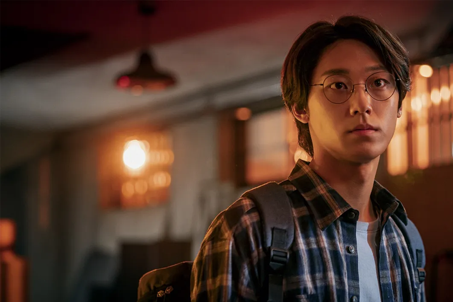 韓國電視劇《Sweet Home》中一位角色在室內背著揹包,復古燈光使場景充滿張力,來自Netflix的圖片。