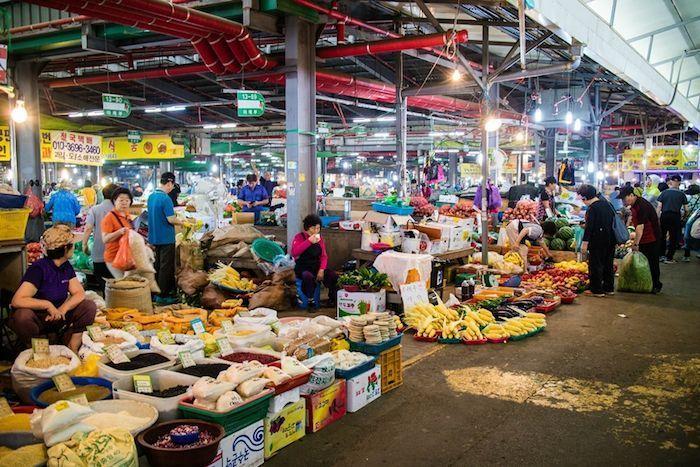 Vendors selling a variety of fruits and vegetables at a Korean 5-day local market, offering a glimpse of traditional marketplace life.