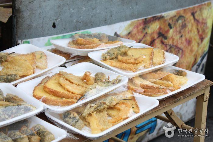 Assorted Korean snacks and fried foods neatly arranged at a stall in a 5-day market, highlighting the variety of market offerings.