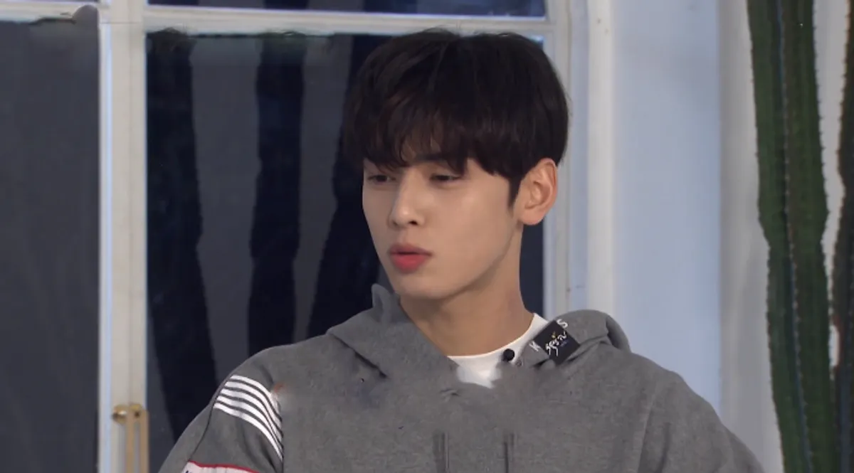 ภาพประกอบผู้ชายในชุดเสื้อฮู้ดสีเทาที่มีพื้นหลังเป็นหน้าต่าง