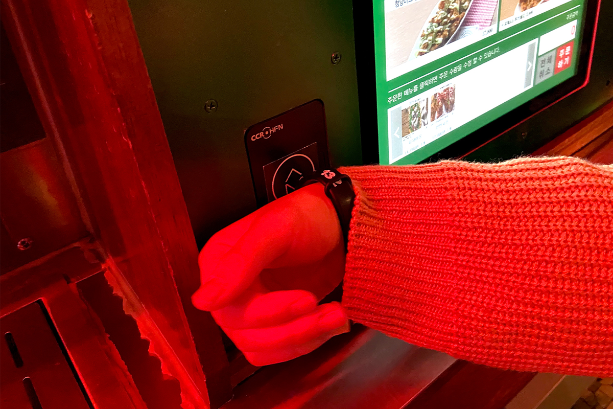 手持腕帶在自助點餐機前操作