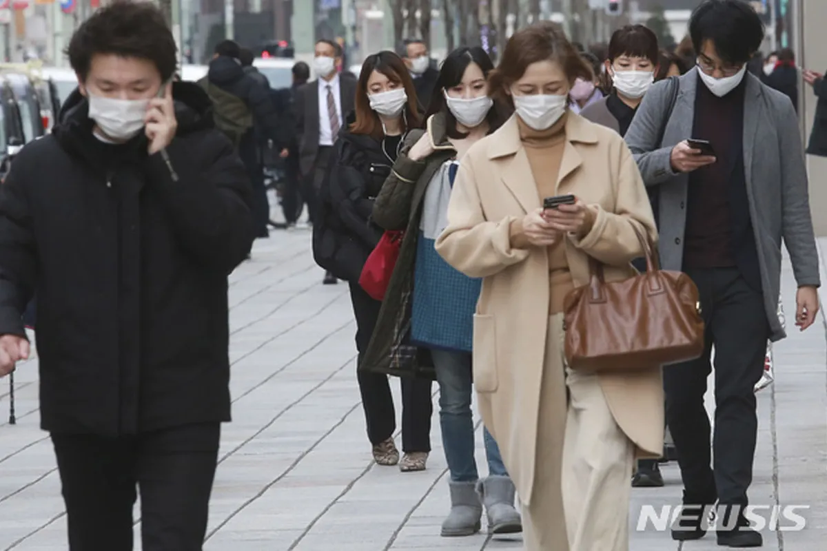 ผู้คนเดินบนถนนในเกาหลีใต้ ขณะใช้โทรศัพท์มือถือ แสดงถึงการขยายระยะเวลาของเคอร์ฟิวในพื้นที่ 
