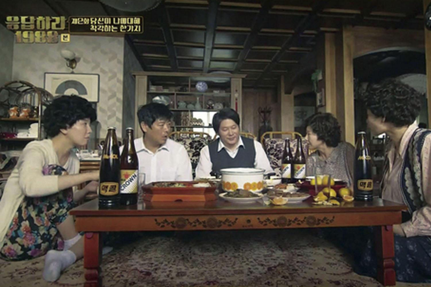 ครอบครัวชาวเกาหลีกำลังนั่งทานอาหารแบบพื้นเมืองรอบโต๊ะพื้นในบ้านที่เกาหลี