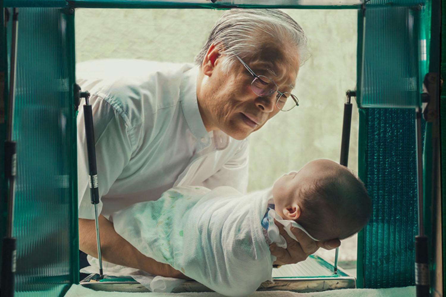 ศาสนาจารย์ในเกาหลีใต้กำลังอุ้มเด็กทารกจาก Baby Box ซึ่งเป็นโครงการช่วยเหลือเด็กทารกที่แม่ไม่พร้อมเลี้ยงดู Cr. Lozierinstitute