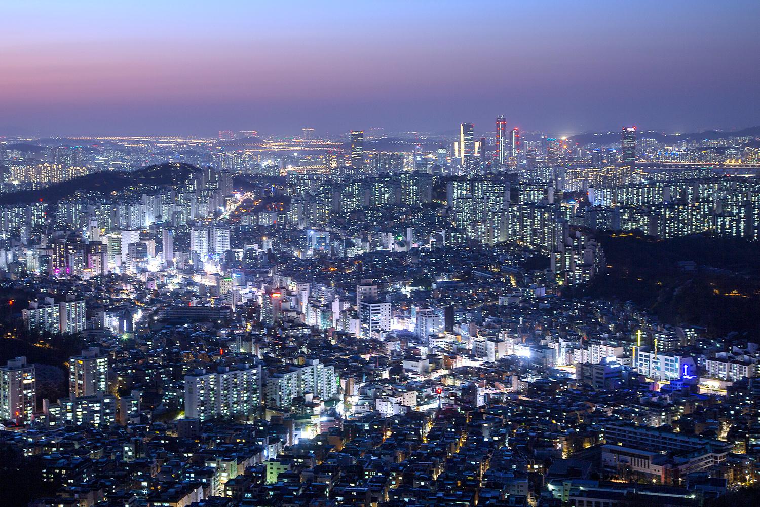 Vista notturna di Seoul con edifici illuminati e strade trafficate.