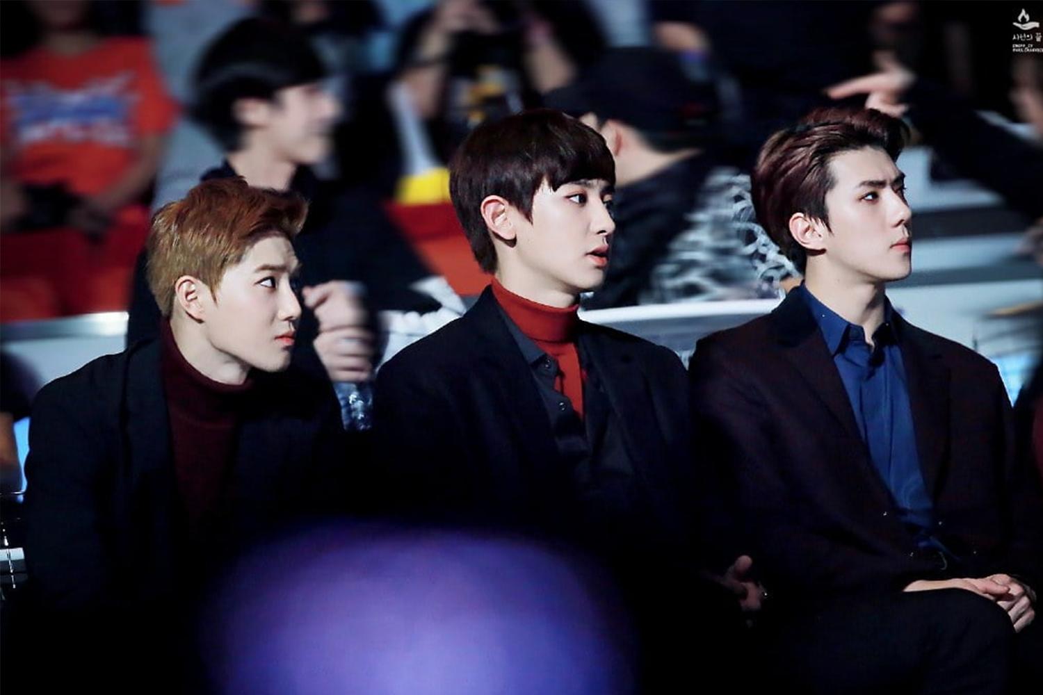 Tre uomini seduti tra il pubblico di un evento o concerto.