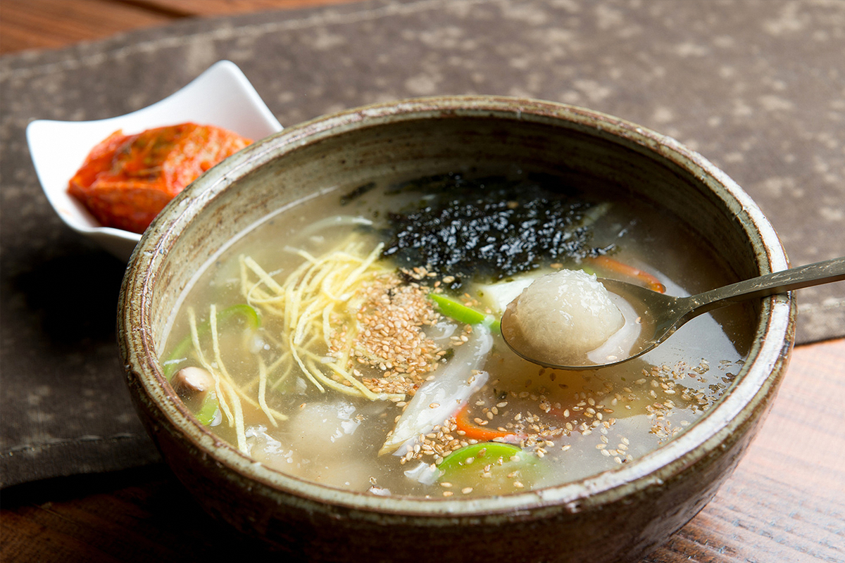 一道傳統的韓國馬鈴薯丸子湯，湯上浮著蔬菜和紫菜。」