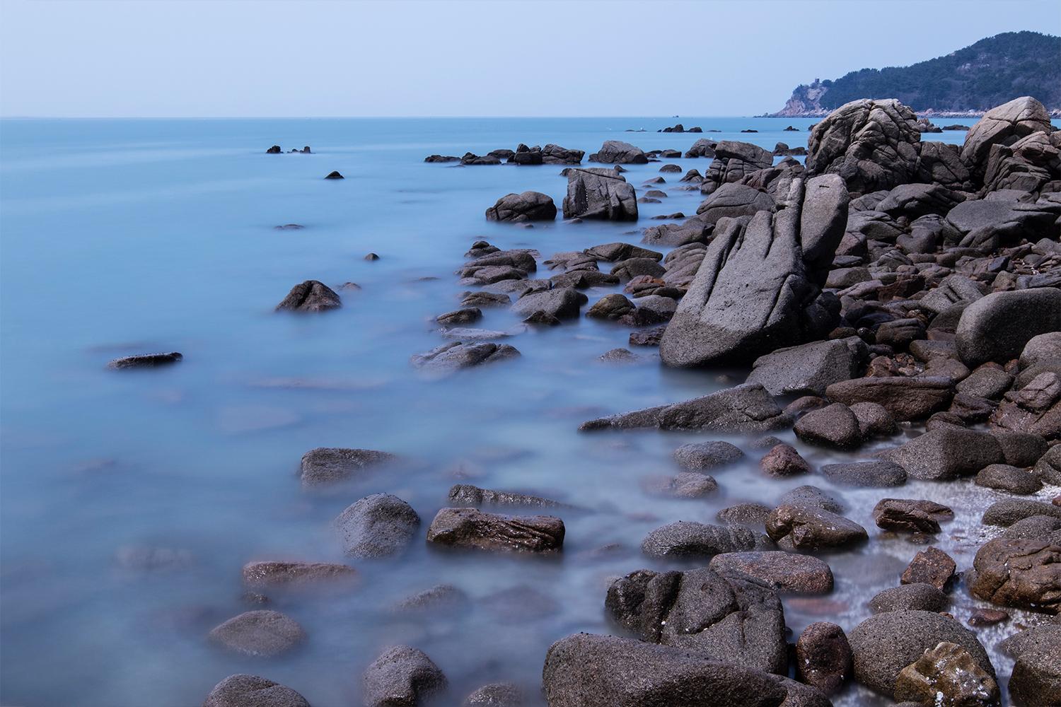 Calm seashore in Incheon with smooth rocks and a distant view of the horizon, emphasizing the city's scenic coastal areas.