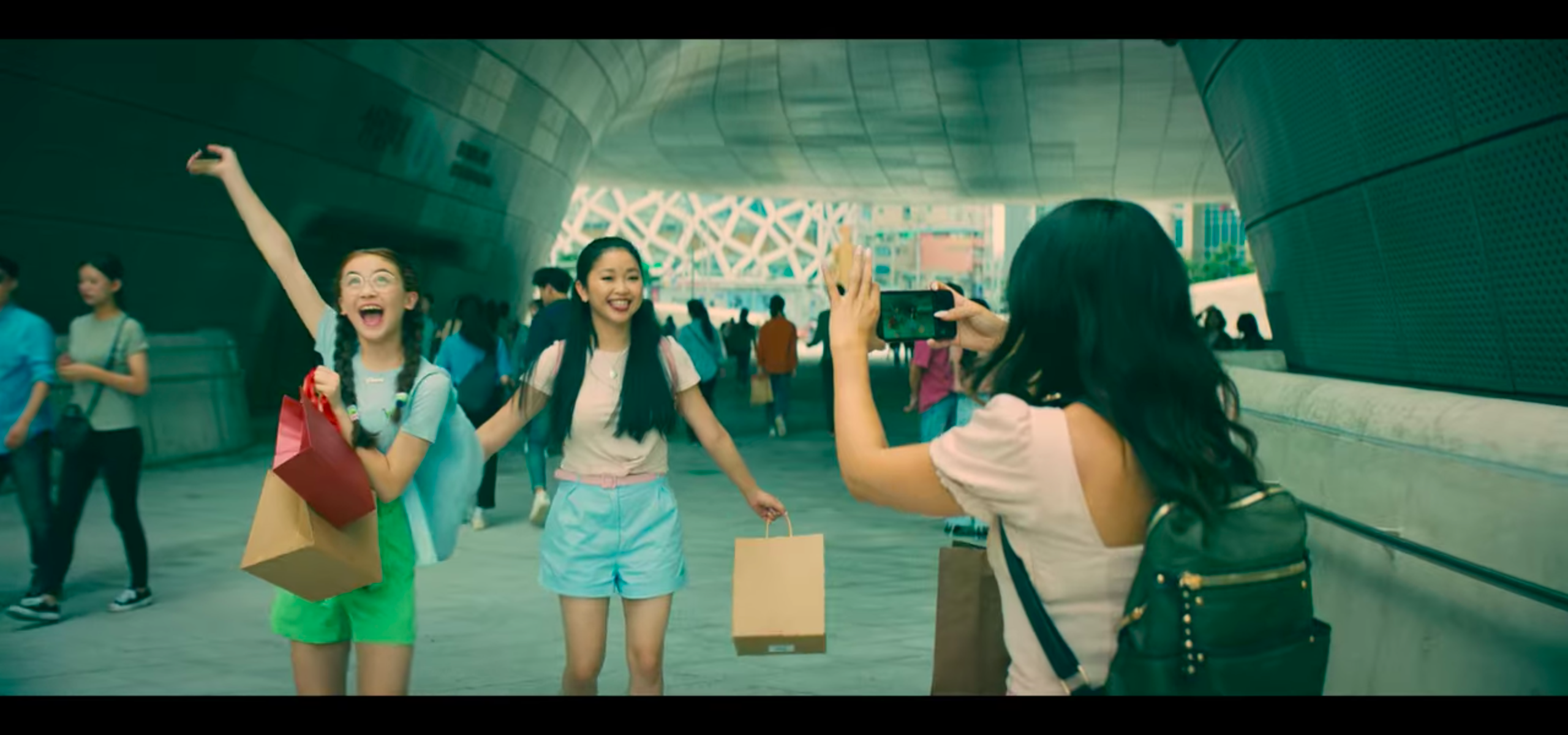 to all the boys: always and forever lara jean and kitty posing for a picture margot is taking at dongdaemun design plaza in seoul
