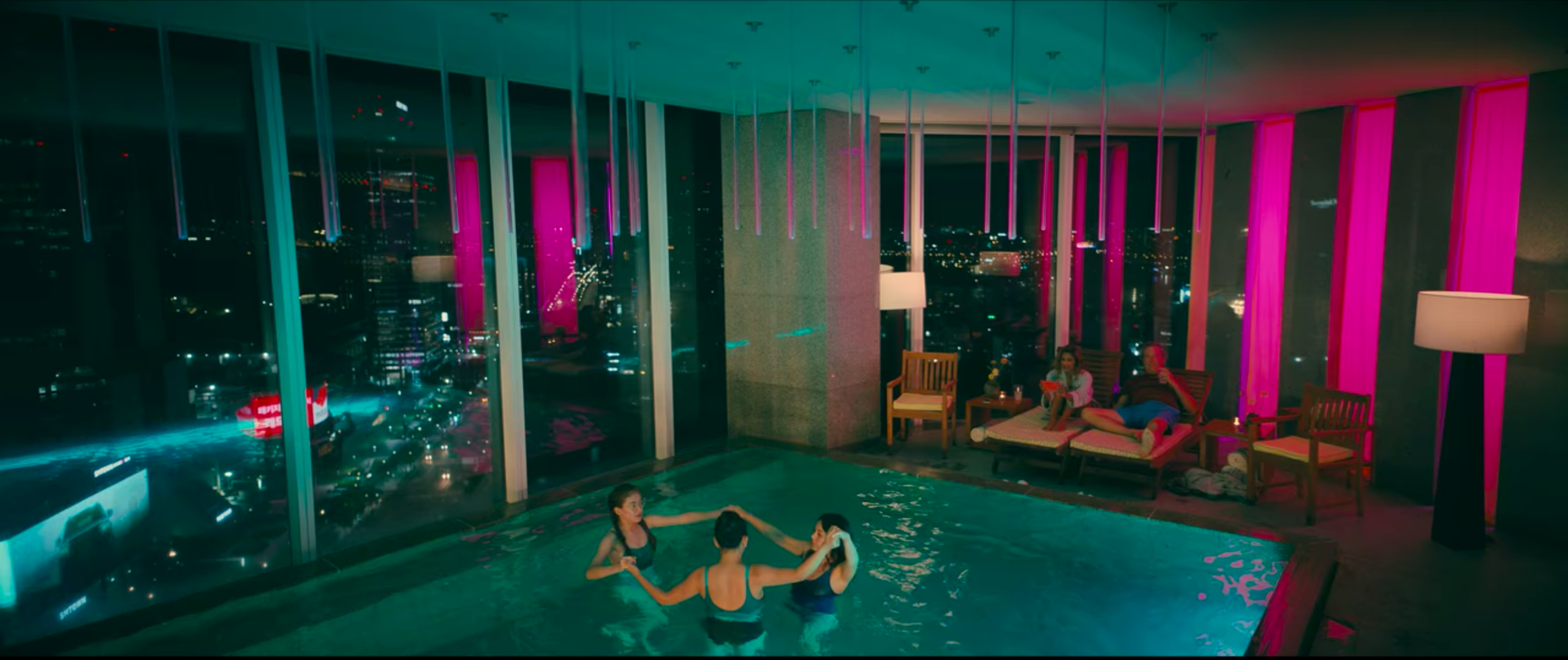 to all the boys: always and forever lara jean, margot, and kitty in the pool at park hyatt seoul and dan and trina lounging in chairs nearby