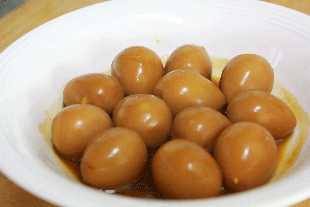 Huevos de codorniz estofados con salsa de soja en un plato blanco, un plato secundario coreano también conocido como banchan